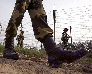 Border Security Force soldiers patrol the fenced border with Pakistan near Jammu