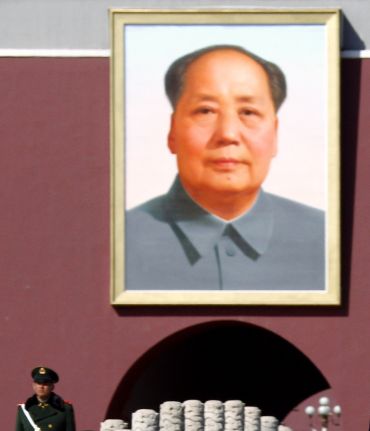 A paramilitary policeman stands guard in front of a giant portrait of the late Chairman Mao Zedong in Tiananmen Square outside the Great Hall of the People in Beijing.