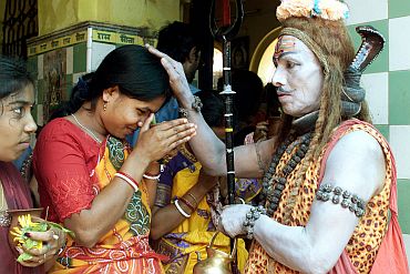 A man dressed as Lord Shiva blesses a devotee on the occasion of Shivratri in Trakeshawar, West Bengal