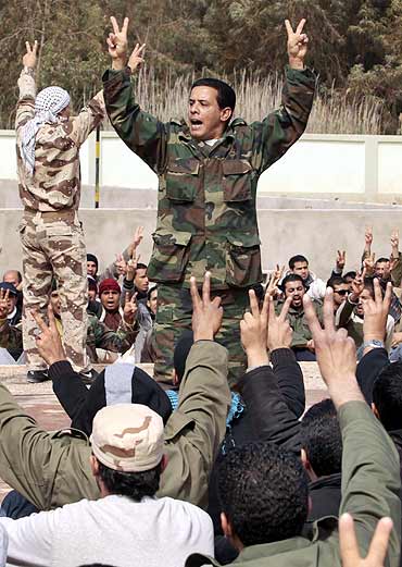 Civilians who have volunteered to join the rebel army shout anti-Gaddafi slogans at a school in Benghazi
