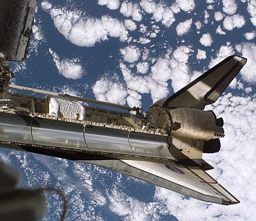 Backdropped by a cloud-covered Earth, Space Shuttle Discovery is featured in this image while docked with the International Space Station during the STS-116 mission