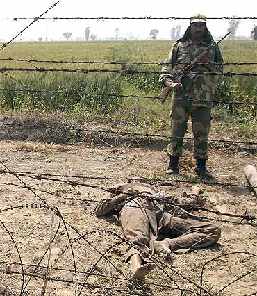 A Border Security Force soldier stands next to the body of a suspected smuggler near the border with Pakistan. A sum of Rs 6.5 million in counterfeit notes was recovered in the operation