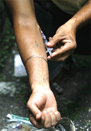 A drug user injects himself with heroin