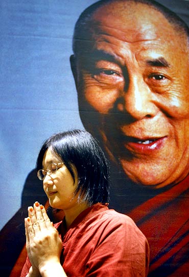 A follower prays in front of a picture of the Dalai Lama