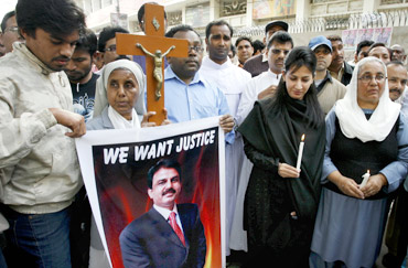 Christians hold a cross and a poster of slain Minister for Minorities Shahbaz Bhatti, during a protest in Hyderabad to condemn his assassination