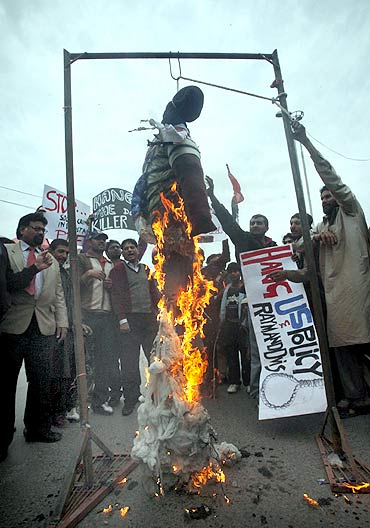 Supporters of a political group hold placards and shout slogans against Raymond Davis as they burn his effigy in Lahore