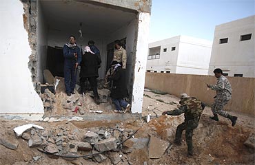 Anti-Gaddafi rebels rush towards a house hit by an air strike in Ras Lanuf