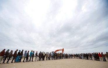 Evacuees line up for food distribution at an UNHCR refugee camp near the border crossing of Ras Jdir after fleeing violence in Libya