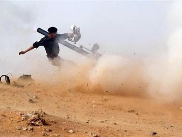 A rebel fighter fires a cannon during a battle near Ras Lanuf