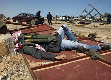 A rebel fighter lies down with ammunition on him near the oil facility of Ras Lanuf