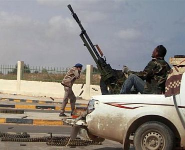 An anti-Gaddafi rebel fires an anti-aircraft gun during clashes with pro-Qaddafi forces in Ras Lanuf