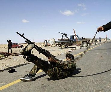 A rebel fighter fires his rifle at a military aircraft loyal to Libyan leader Muammar Gaddafi at a checkpoint in Ras Lanuf