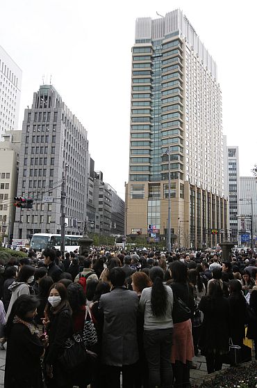 People stand outdoors after evacuating from nearby buildings in Tokyo's financial district