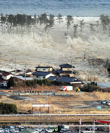 A massive tsunami sweeps in to engulf a residential area after a powerful earthquake in Natori, Miyagi Prefecture in northeastern Japan