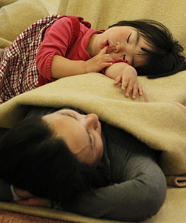 Passengers sleep at a lobby as they wait for their transportation at Haneda Airport in Tokyo