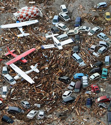 Cars and airplanes swept by a tsunami are pictured among debris at Sendai Airport