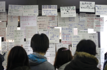Residents search for the names of their missing family members and relatives at a temporary information centre organised by the local government after their villages were hit by the earthquake and tsunami in Sendai, northeastern Japan