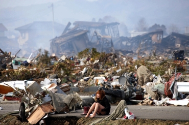 A woman cries while sitting on a road amid the destroyed city of Natori, Miyagi Prefecture