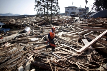 An emergency worker walks amidst debris in an area hit by an earthquake and tsunami in Kuji, Iwate
