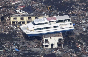 A ferry is perched on top of a house in the aftermath of an earthquake and tsunami in Otsuchi, Iwate