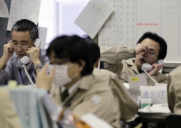 Workers at the disaster response headquarters speak on telephones in Fukushima, northern Japan
