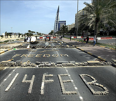 Anti-government protesters form the words Freedom and 14 Feb with bricks as they block the roads from riot police at the junction of Bahrain Financial Harbour in Manama