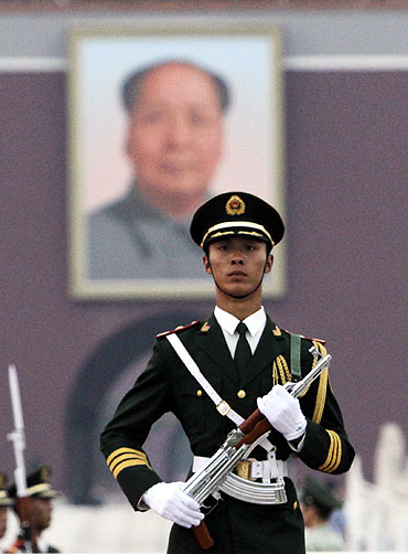 A paramilitary policeman stands guard in front of a portrait of the late chairman Mao Zedong on Tiananmen Square in Beijing