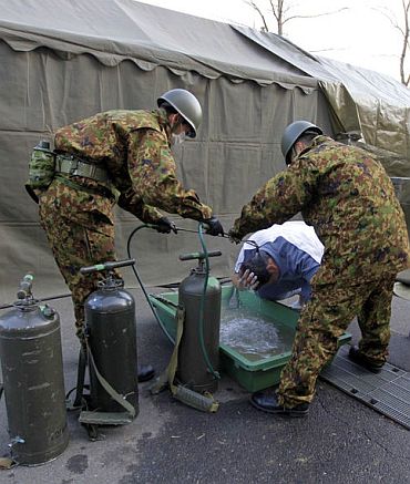 Soldiers help clean a man who may have been exposed to radiation from the damaged Fukushima nuclear power plant