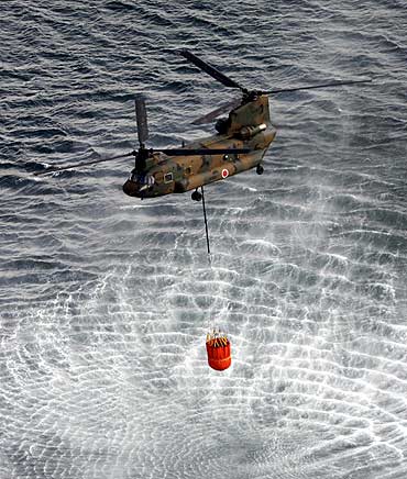 A Japan Air Self-Defense Force CH-47 Chinook helicopter collects water from the ocean to drop on the reactors at the Fukushima Daiichi nuclear plant