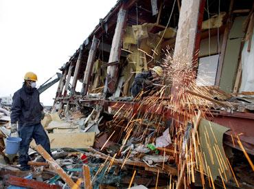 Emergency workers cut metal debris on a building in Yamada, Iwate Prefecture