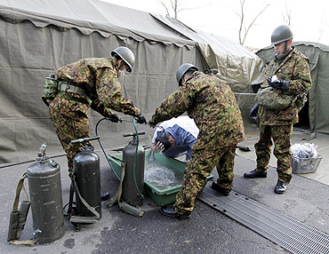 A man who was evacuated from the vicinity of Fukushima's nuclear power plant washes his head at Japan Ground Self-Defense Forces makeshift facility to cleanse people who might have been exposed to radiation