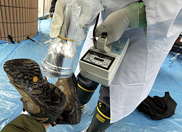 Medical staff screen the boots of a person who is concerned over radiation exposure at a public welfare center in Niigata, northern Japan