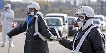Police officers wearing respirators guide people to evacuate away from the Fukushima plant