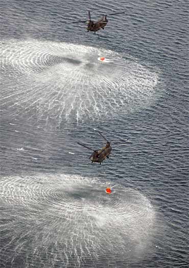 Japan Air Self-Defence Force helicopters collect water from the ocean to drop on the reactor