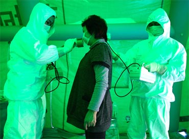 Medical staff use a Geiger counter to screen a woman for possible radiation exposure