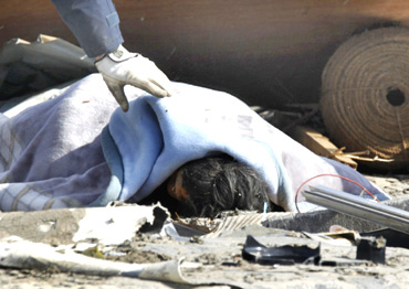 A police officer checks a dead body at a village destroyed by the earthquake and tsunami in Ofunato, Iwate Prefecture