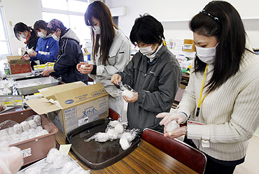 Volunteers make rice balls for survivors at a shelter in a village destroyed by the earthquake and tsunami