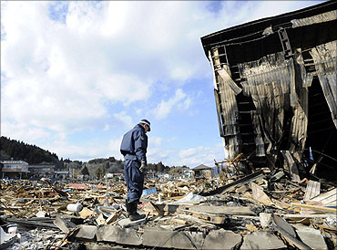 A police officer stands at an area destroyed by an earthquake and a tsunami in Kesennuma city, Miyagi Prefecture