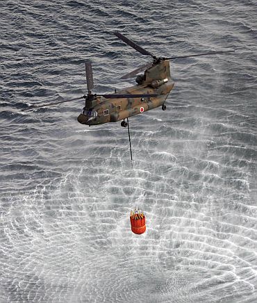 A helicopter collects water from the ocean to drop on reactors at the Fukushima nuclear plant