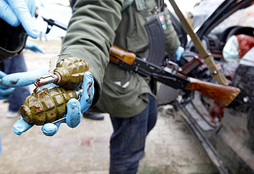 A rebel shows hand grenades found on fighters loyal to Gaddafi