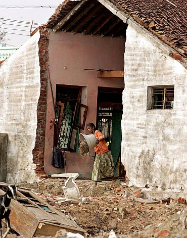 An tsunami survivor throws debris out of her damaged house in Nagappattinam, Tamil Nadu in January 2005