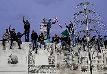 Youths standing on a wall of the house of Libya's leader Muammar Gaddafi form a human shield in Tripoli