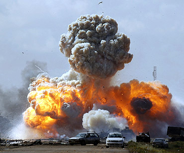 Vehicles belonging to forces loyal to Gaddafi explode after a NATO air strike, along a road between Benghazi and Ajdabiyah
