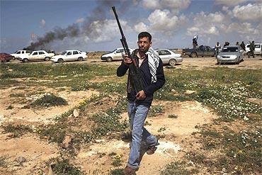 A rebel fighter carries his weapon at the scene of what residents said was a French airstrike