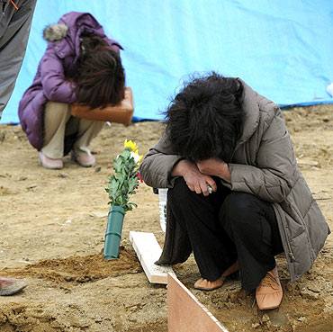 Relatives mourn the victims of the Japan disaster at a mass grave