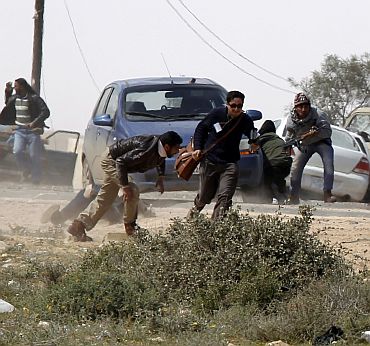 Foreign journalists take cover during an air strike at a rebel fighters checkpoint in Al Ugaila area along a road between the towns of Brega and Ras Lanuf