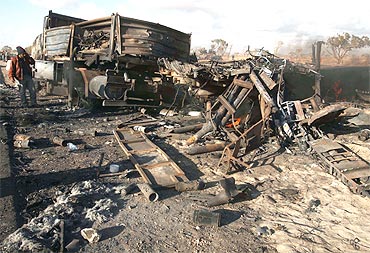 A man looks at destroyed weapons belonging to Gaddafi's forces, after a coalition air strike near Benghazi