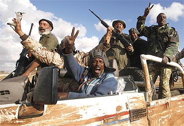 Rebels celebrate in a vehicle along the road near Benghazi