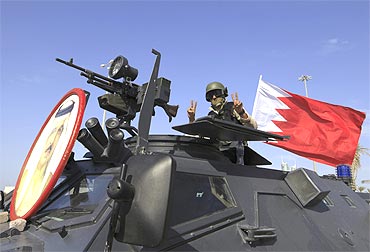 A soldier from the GCC forces flashes the victory sign as he guards the entrance to Pearl Square
