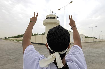 An anti-government protester shows the victory sign to guards at the watchtower of the palace
